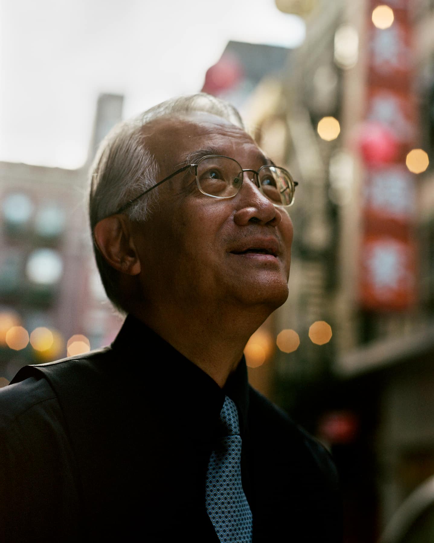 Wellington Chen looking up, the lights of the street soft behind him
