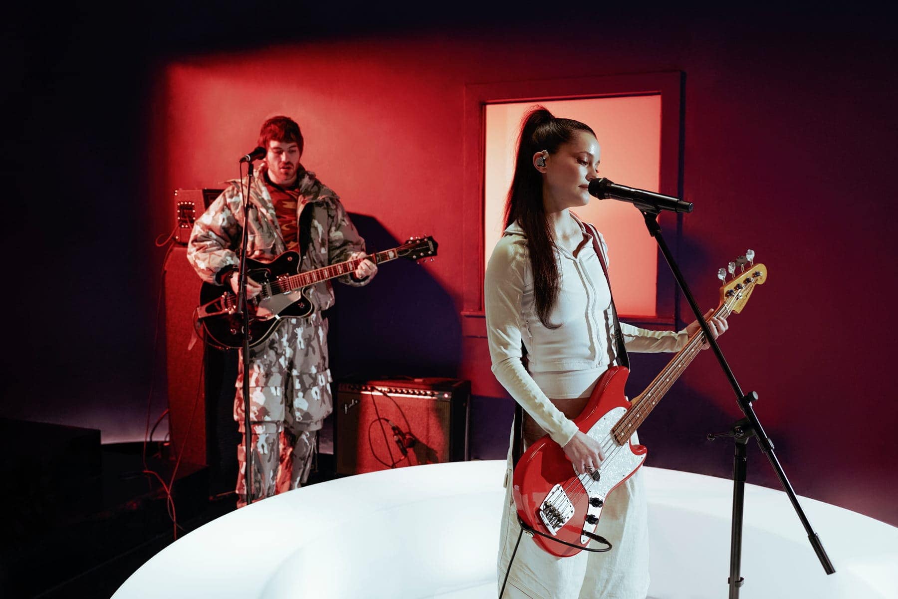 Fcukers performing on the RADAR set, Shanny Wise on bass at the mic and Jackson Walker Lewis on guitar in a red-lit room
