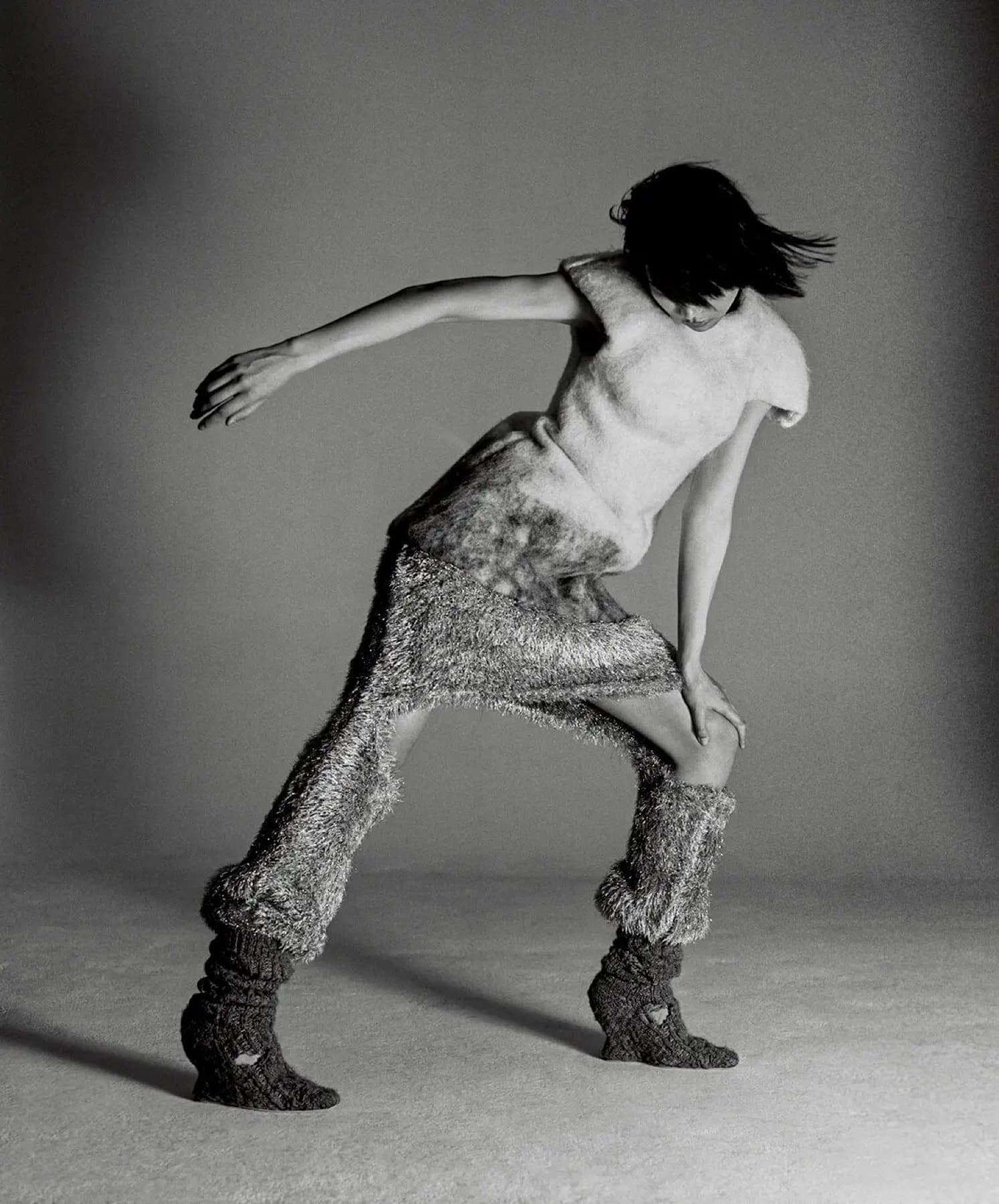 Model mid-motion in a knit tank and textured trousers with matching leg warmers